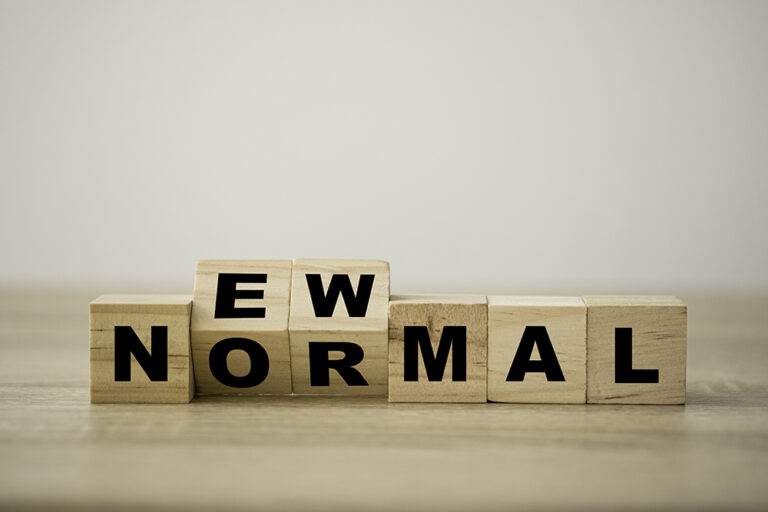 Hand flipping wooden block cubes for new normal wording. The world is changing to balance it into new normal include business , economy , environment and health.